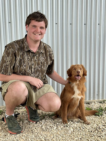 young man knealt next to a Nova Scotia Duck Tolling Retriever