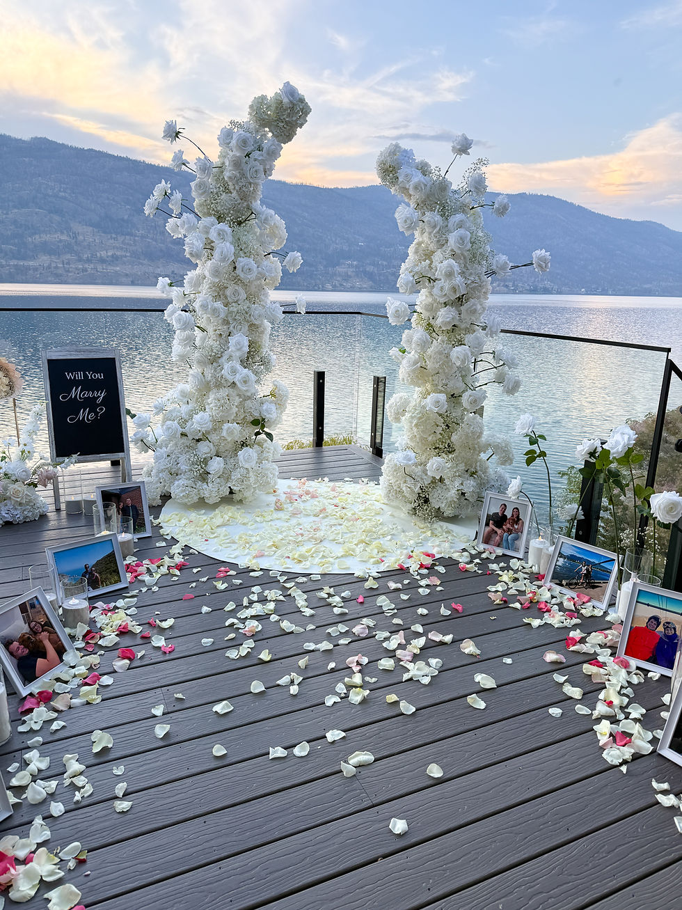 Romantic at-home proposal in the Okanagan Air bnb proposal featuring candlelit aisle, fresh rose petals, tall white roses, and customizable sign styled by Pickadilly’s.
