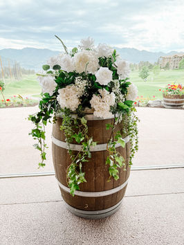 eal Touch floral arrangement styled on a wine barrel for an outdoor Okanagan wedding