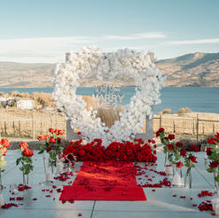 Engagement proposal Kelowna white floral heart setup with candles and romantic lake view in Okanagan