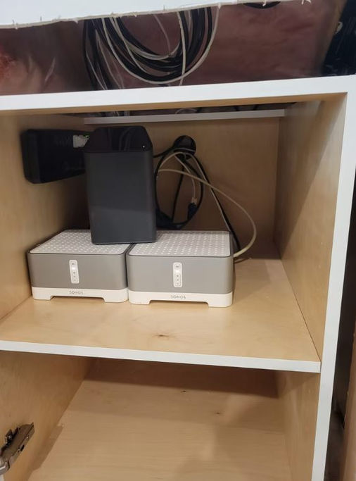 Inside cabinet showing Sonos equipment and organized low-voltage wiring and cables.
