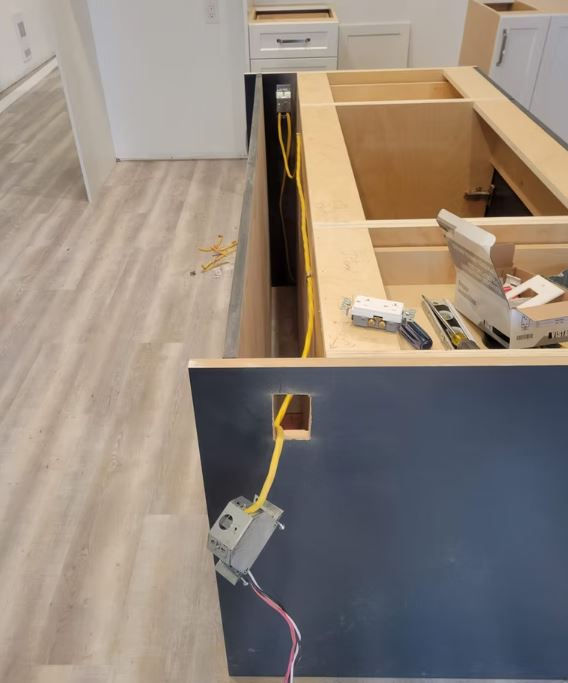 Kitchen island cabinet framing with exposed electrical box and wiring before countertop installation.