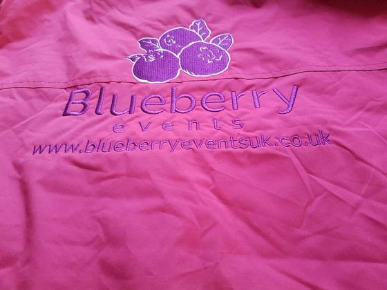 pink polo shirt with purple embroidered Blueberry Events logo on the back