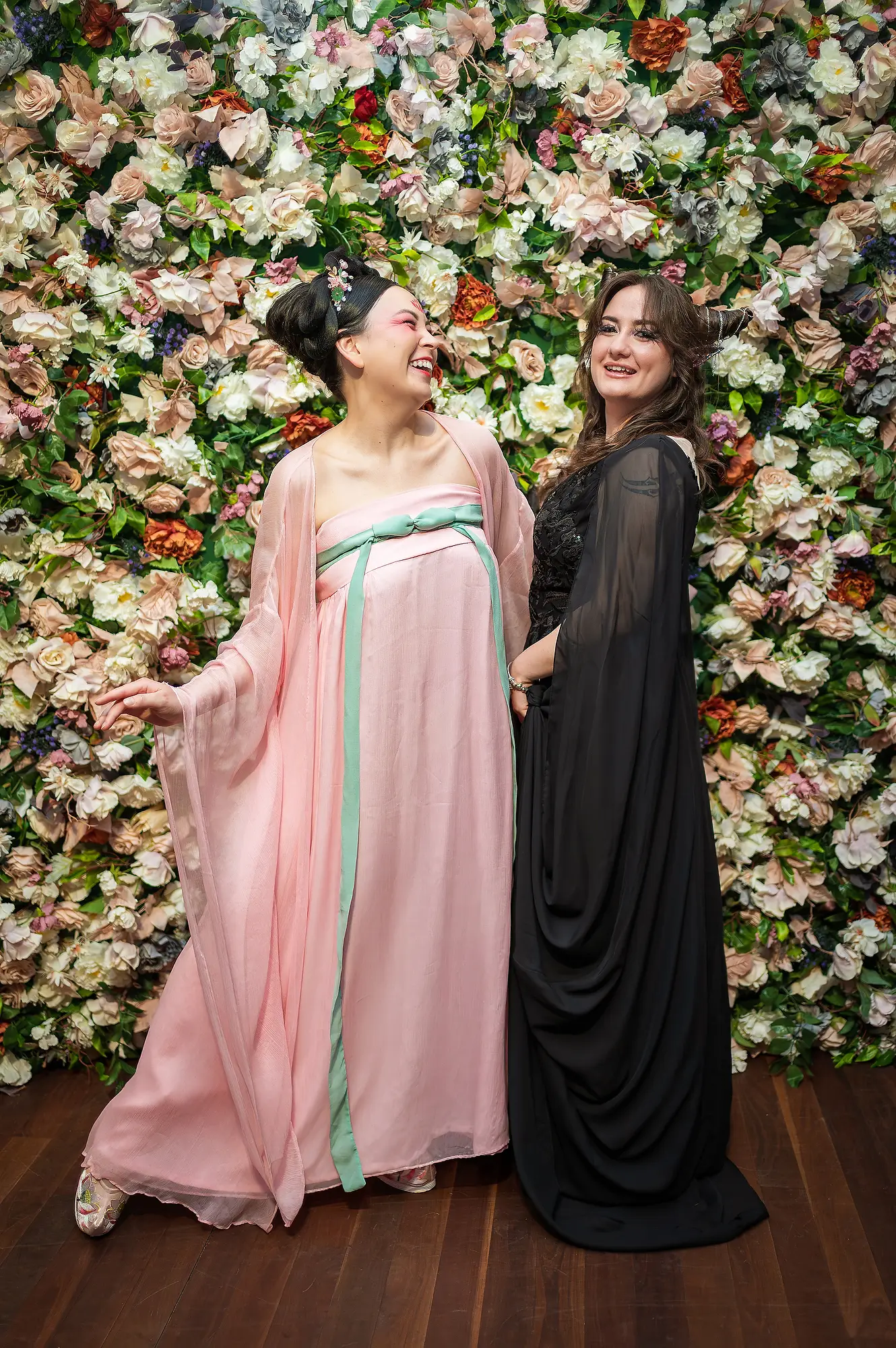Portrait of two women laughing in front of floral backdrop at Celestial Events Brisbane
