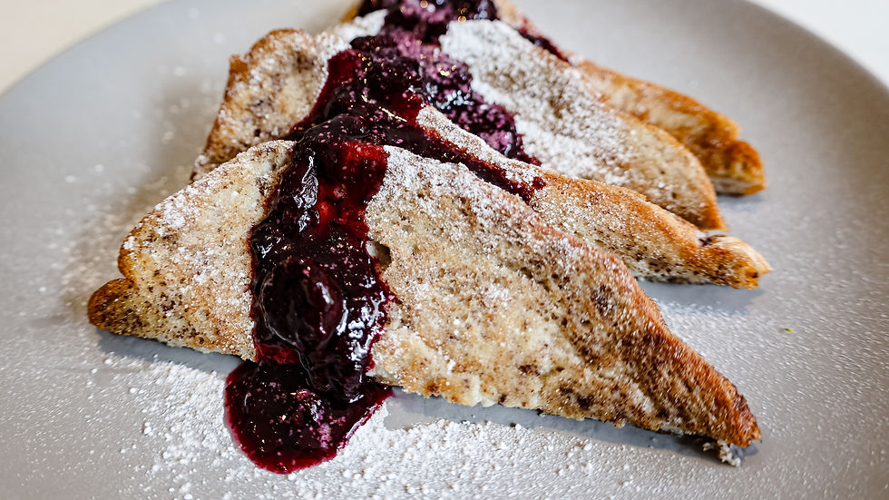 French toast on a grey plate with blueberry compote and icing sugar on top.