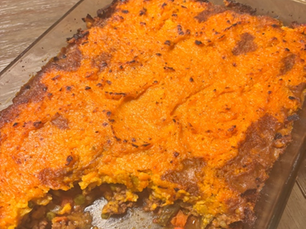 sweet potato shepherd's pie in a glass casserole dish. corn, carrots, and ground beef are visible in the slice.