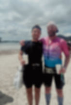 Two men embracing on a beach, holding cups