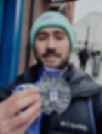 Man holding up a silver medal with blue ribbon
