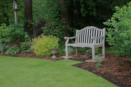 White wooden bench in a landscaped yard
