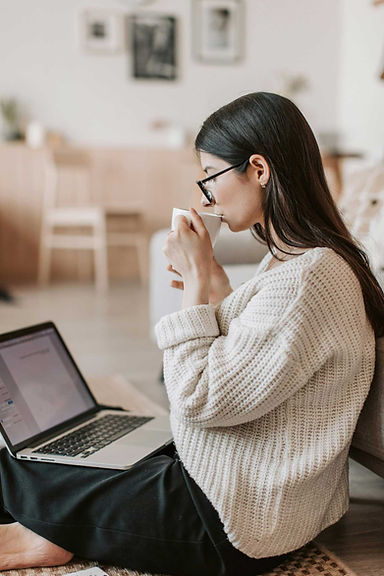 Young woman drinking coffee and working at laptop