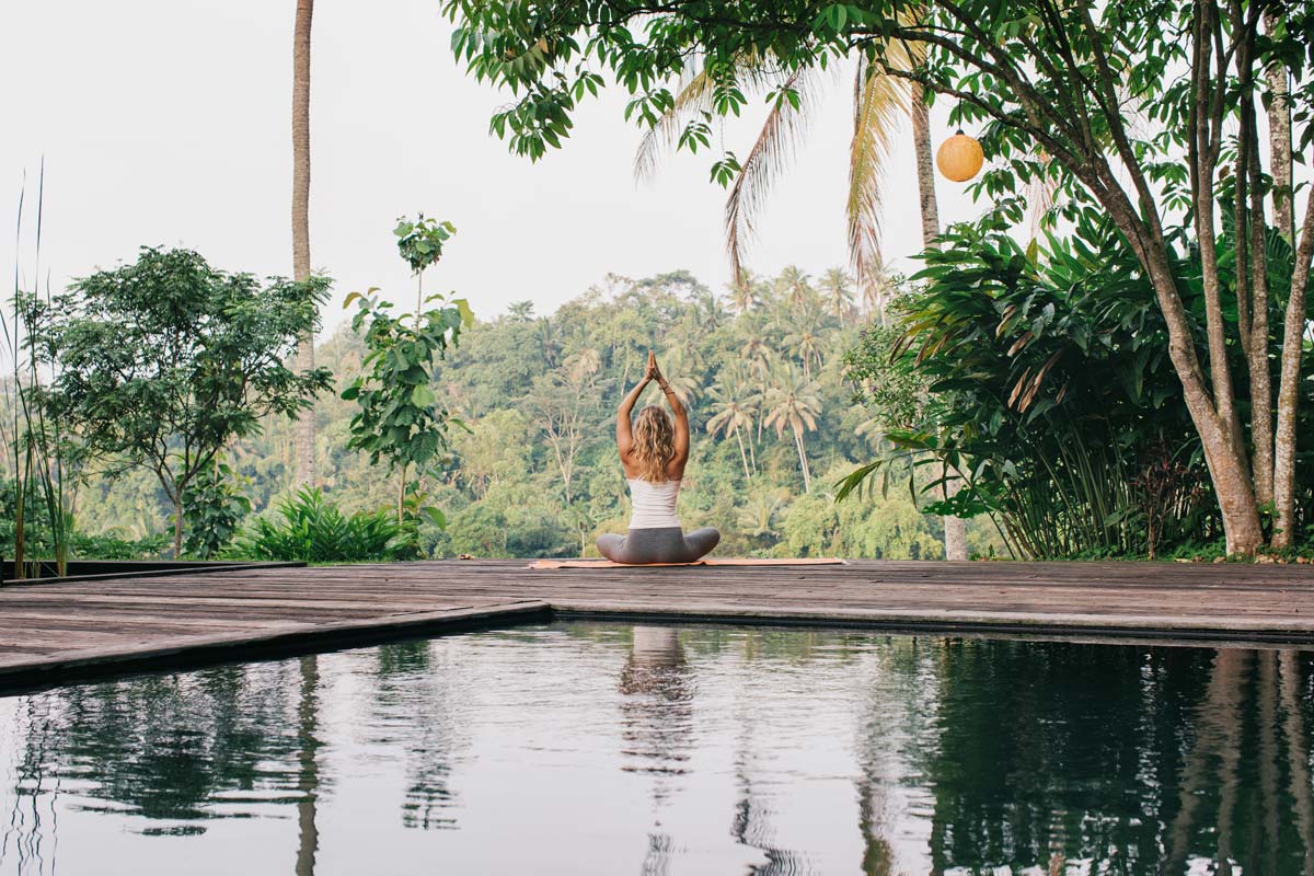 young-woman-practicing-yoga-by-pool-at-tropical-resort.jpg