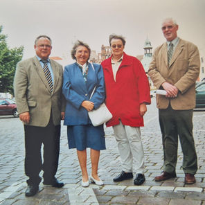 4 Menschen in einer Reihe draußen stehend an einem Marktplatz