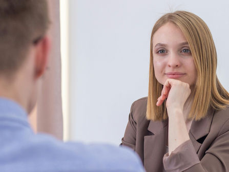 Kvinne og mann som snakker sammen. Han sitter med ryggen til.