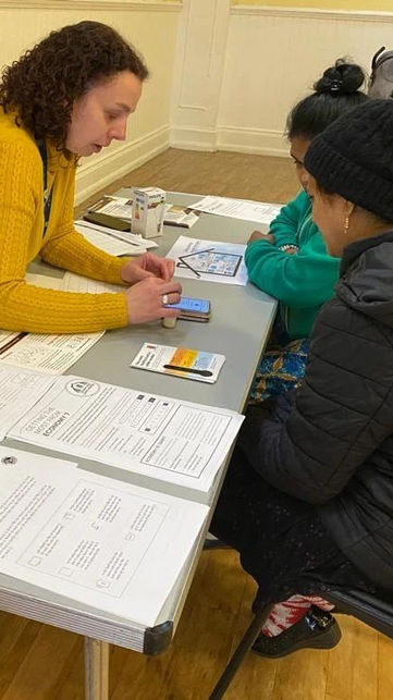 A specialist advisor helping two women with filling out legal forms.