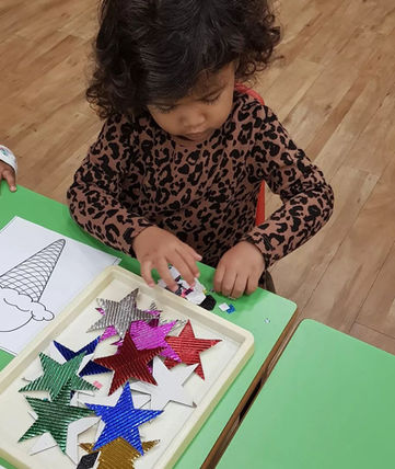 A toddler enjoying playing with different paper shapes and drawing.