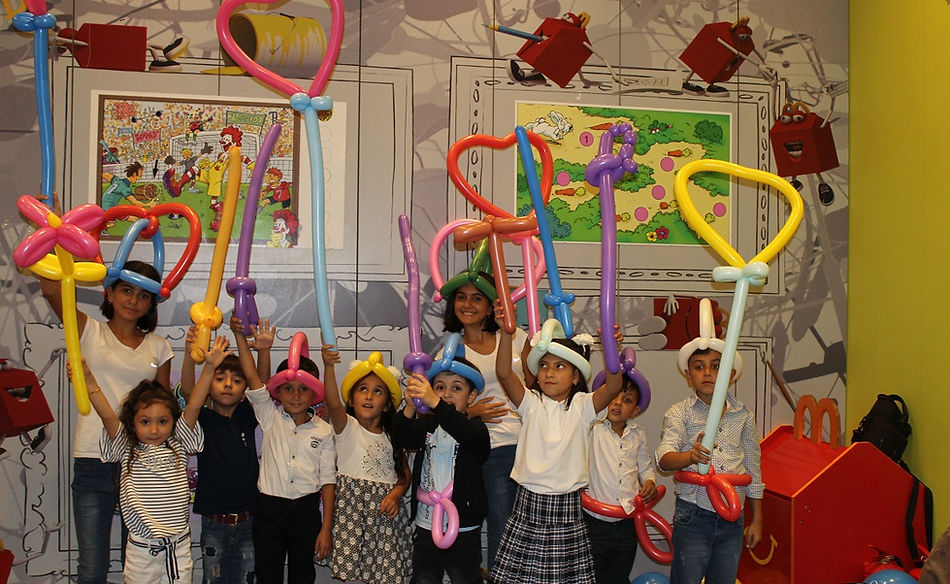 All the children are holding different balloon twisting creations in their hands. Some have hearts, others have butterflies,