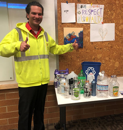 A man giving the thumbs up next to a table of recycling.
