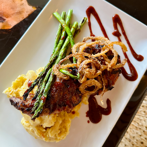 pork chop served over garlic mashed potatoes, topped with asparagus and crispy fried onions