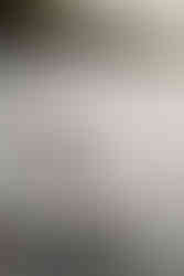 Bride and groom stand on rocky edge of a lake during a