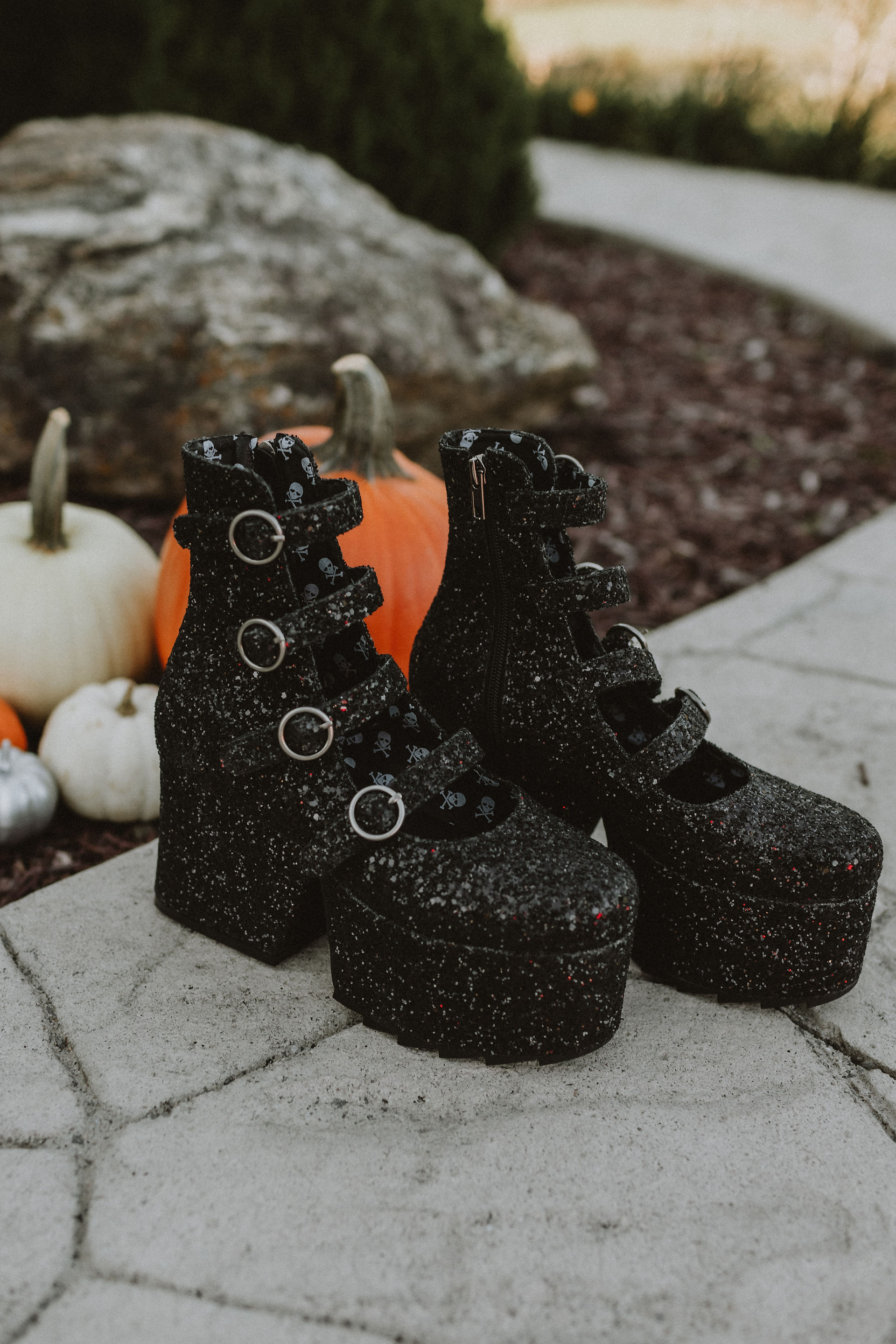 platform sparkly black buckle up shoes on stone pathway with pumpkins behind them