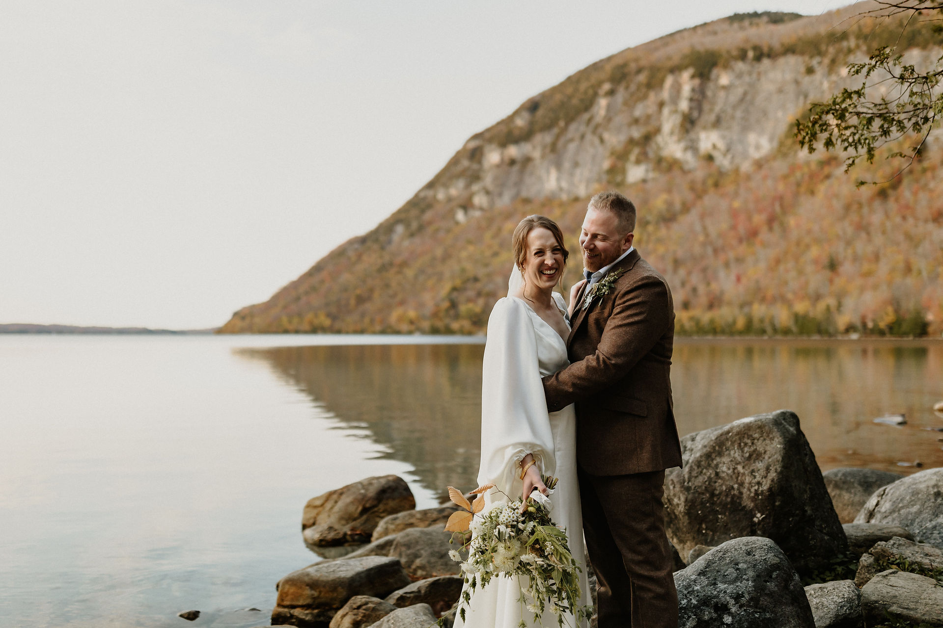 Bride and groom standing on the rocks at sunset at Lake Willoughby in the Northeast Kingdom of Vermont
