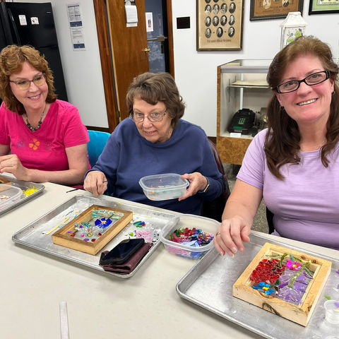 Three women smiling with their art