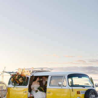 Bride and groom pose in front of a yellow vintage VW photo booth bus during a cirtus-inspired styled wedding shoot at The View at South Bay in Green Bay, WI
