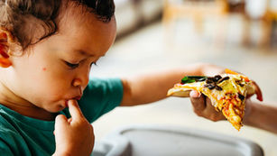 Un niño pequeño comiendo comida procesada