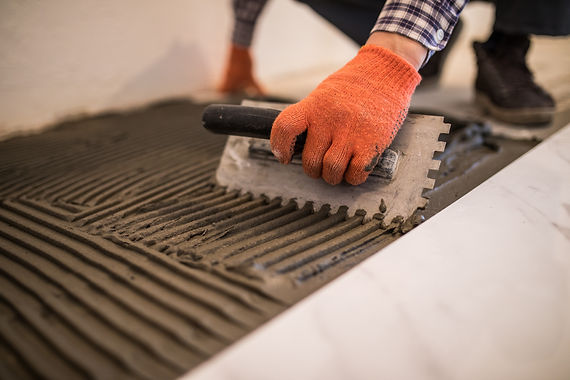 laying-ceramic-tiles-troweling-mortar-onto-concrete-floor-preparation-laying-white-floor-t
