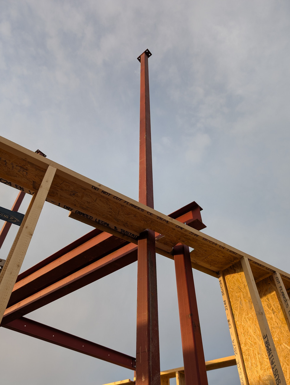 Photograph of a tall steel column going through a timbe frame