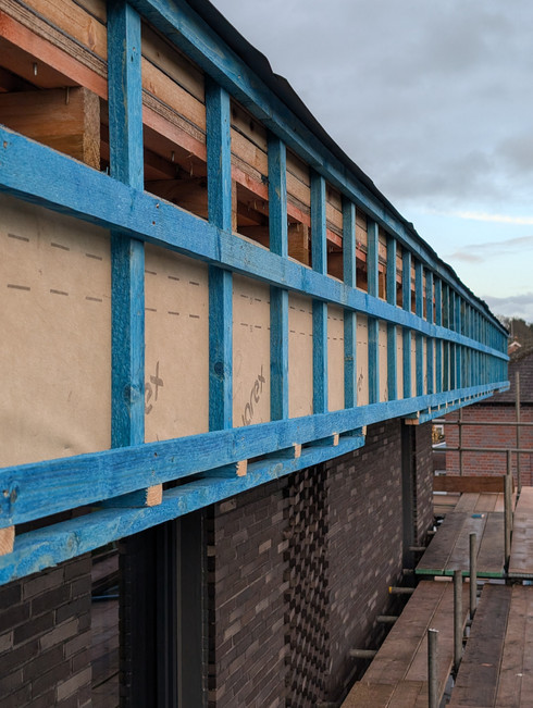 photo of the side of a roof under construction, blue timber battens on the fascia edge of a flat roof
