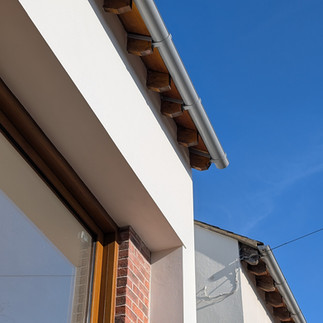 Photo of an eaves of a home with a pitched roof and white render walls