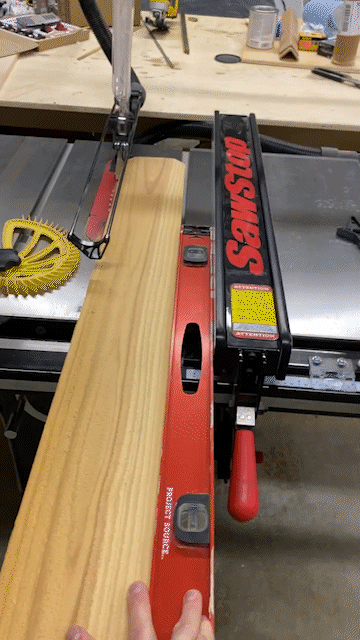 GIF using a 4' level to straight line rip a board on table saw