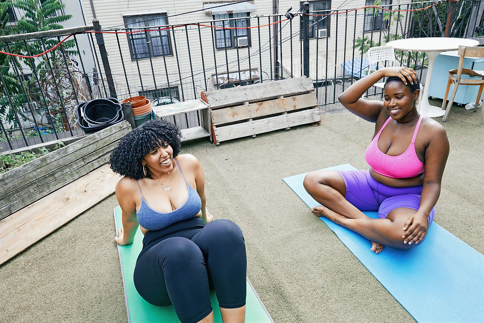 Portrait de deux femmes portant des leggings, assises sur des tapis de yoga, souriantes, vue de face.