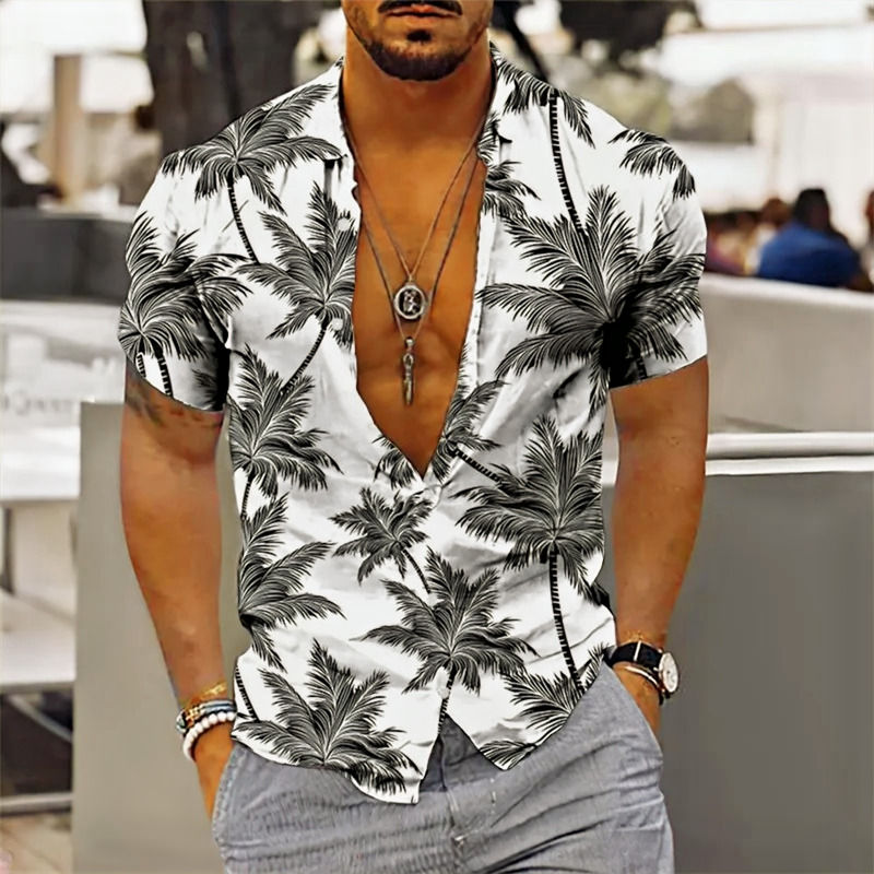 Portrait d'un homme portant une chemise imprimée tropicale, des colliers, des bracelets, une montre bracelet en cuir noir, un pantalon gris, vue de face.