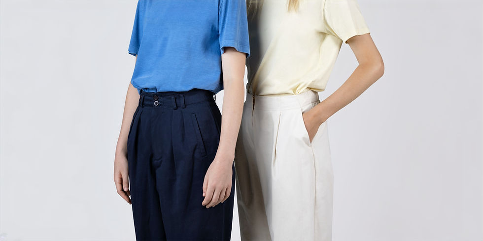 Portrait de deux personnes portant des pantalons chinos noir et beige et des chemises, bleue marine et jaune, vue de côté.
