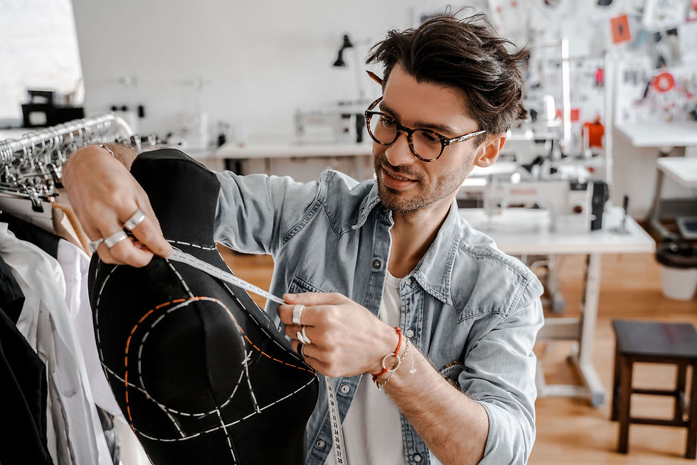 A men's fashion designer measuring the shoulders of a blazer with a tailor's ribbon, front view.