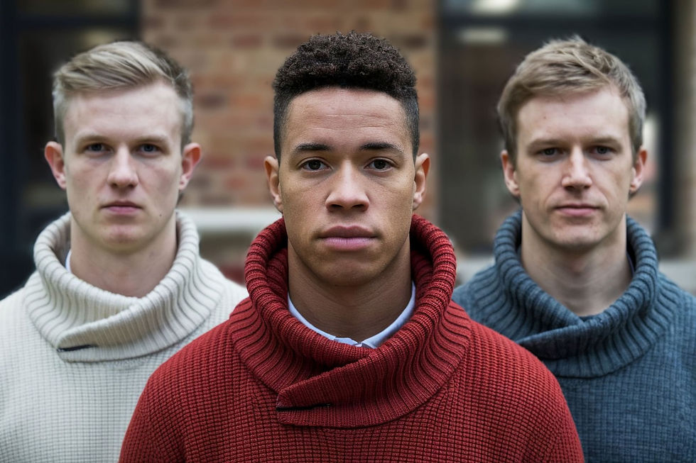 Portrait of three men wearing turtleneck sweaters, beige, red and blue, front view.