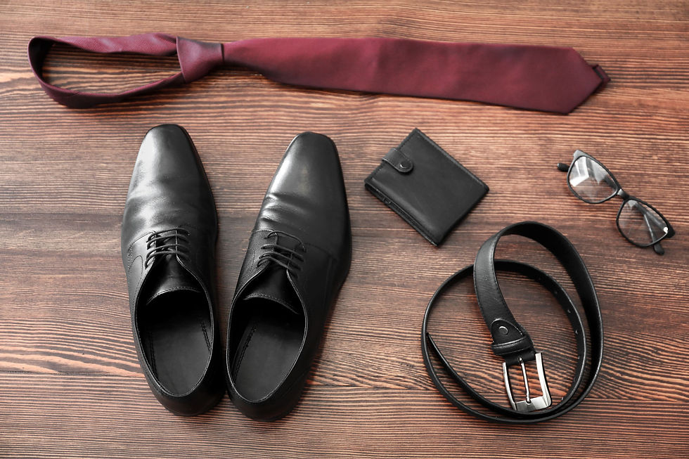 Black shoes and accessories for men lying on a floor.