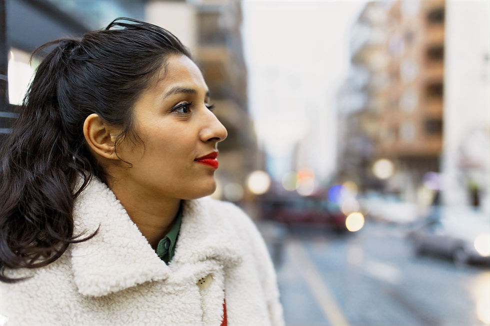 Portrait of a woman wearing a white winter coat, standing in the city, front view.