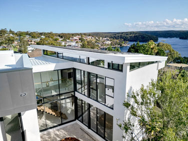 A large white architectural home with black windows overlooking river views