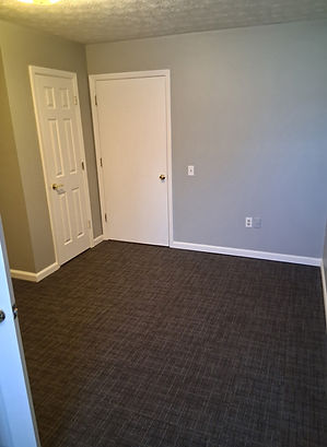 Empty bedroom with closed white doors and gray walls on carpeted floor.
