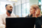 What does cybersecurity look like in practice? Two people talking in front of a computer.