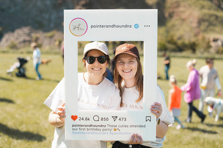 Two guests posing with a branded photo frame at a corporate event – photo booth social content.