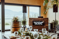 Boogie Beats DJ booth behind a beautifully set wedding table with glassware and scenic windows.