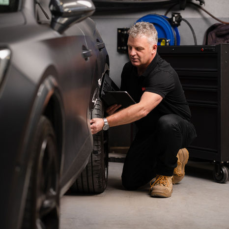 Automotive repair mentor inspecting vehicle panel in workshop, photographed by Display commercial photographer in NZ.