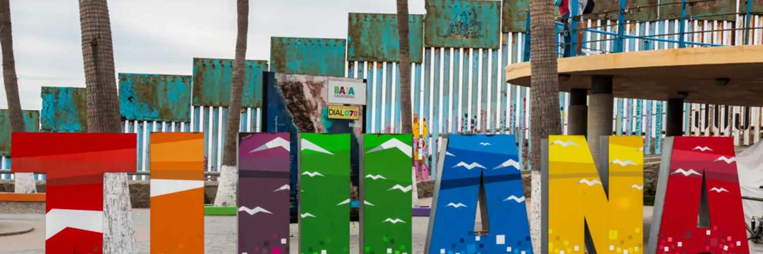 Cartel de Tijuana con la insignia Aquí empieza la patria cerca del muro fronterizo