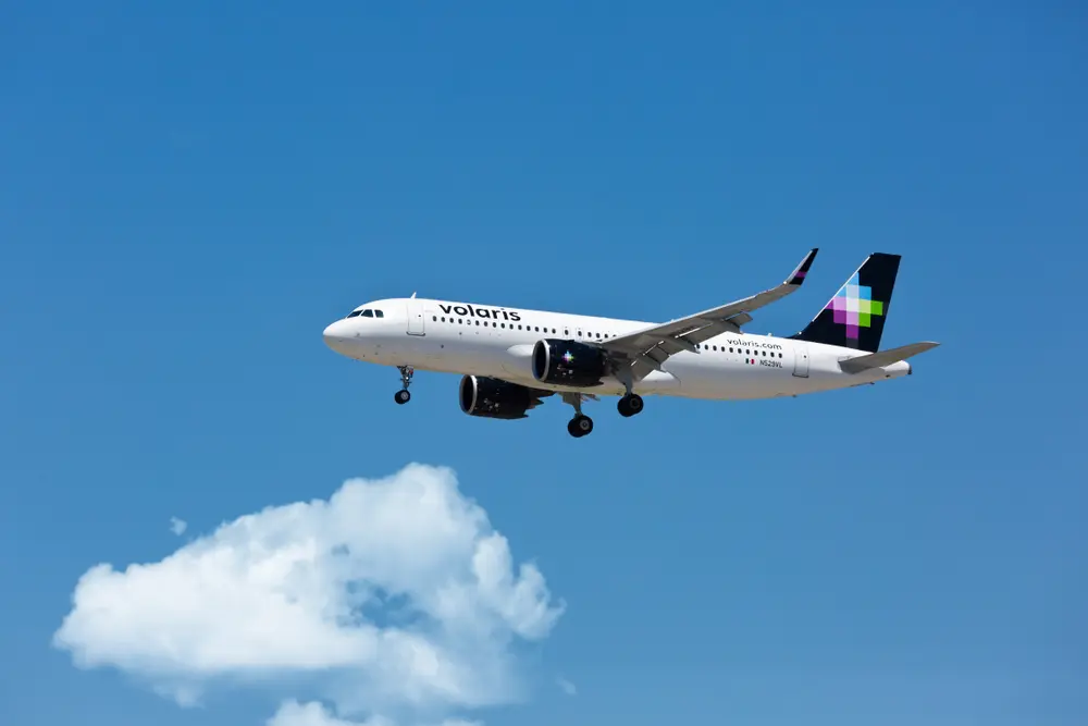 Avión de Volaris volando bajo un cielo azul