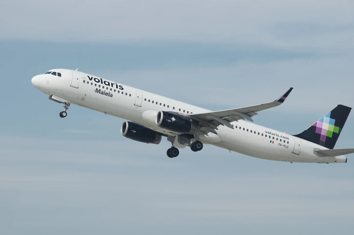 Avión de Volaris en pista, con el logo y el mensaje "100 aviones para que más personas viajen bien".