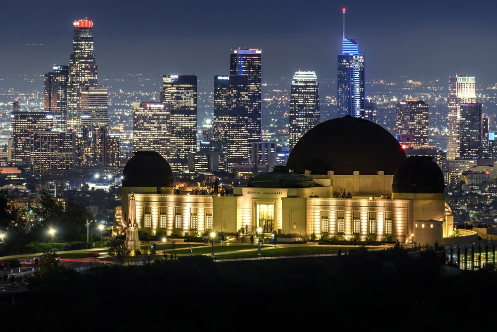 Griffith Observatory at night, with skyscrapers in the background.